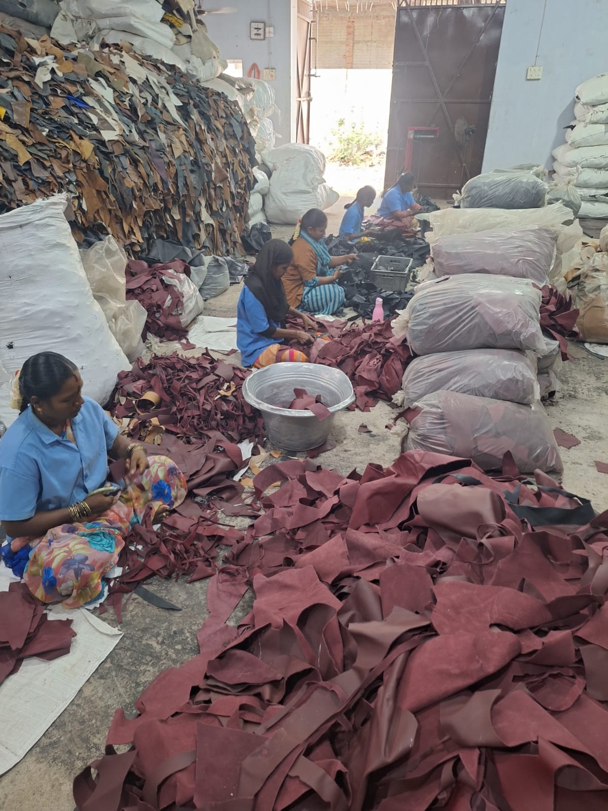 Workers manually sorting leather scraps on the floor