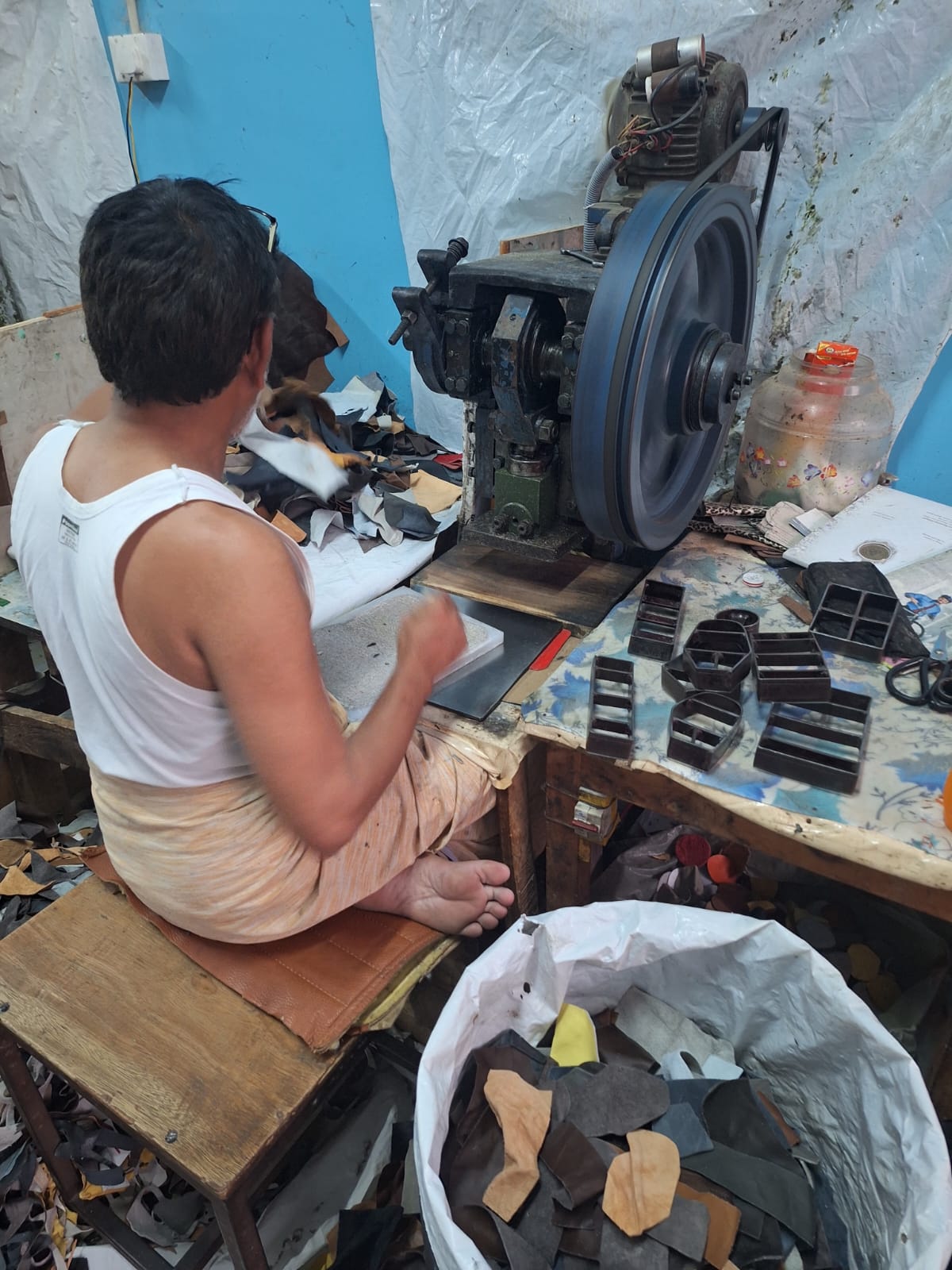 Worker operating clicking die-cutting machine with metal dies